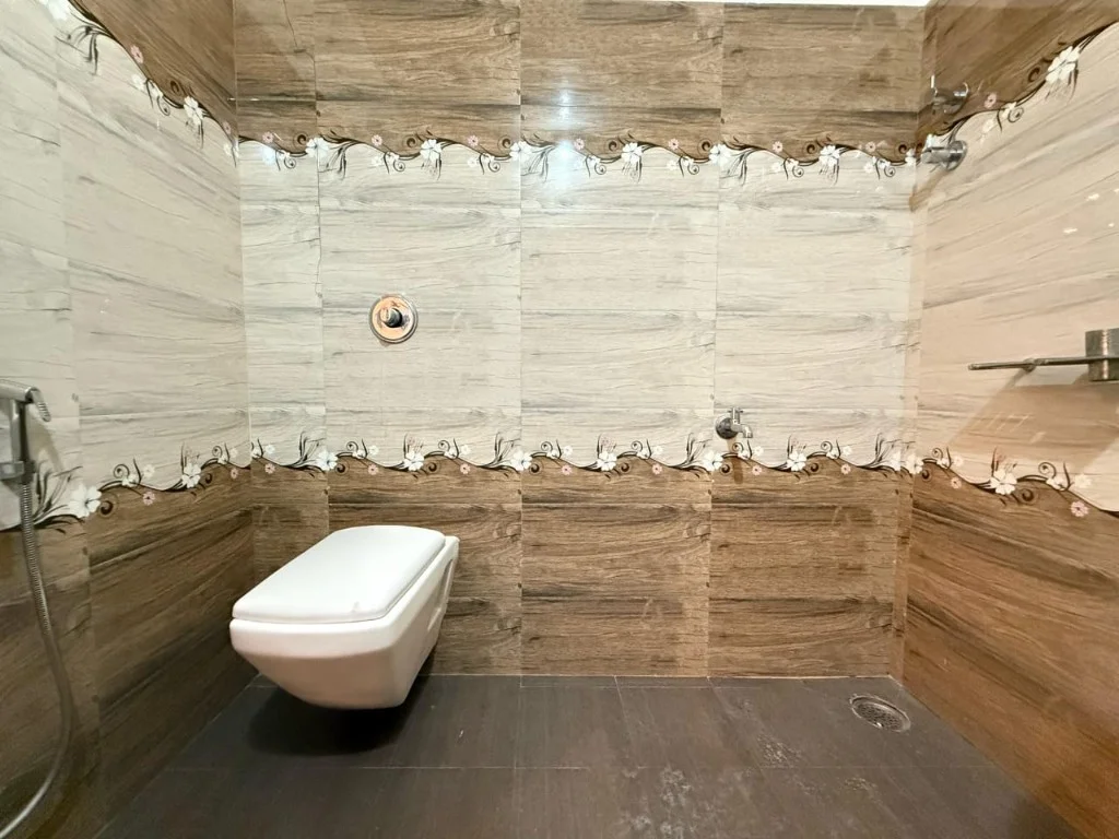Clean ensuite bathroom with floral tile borders at Resort P2 Chikmagalur