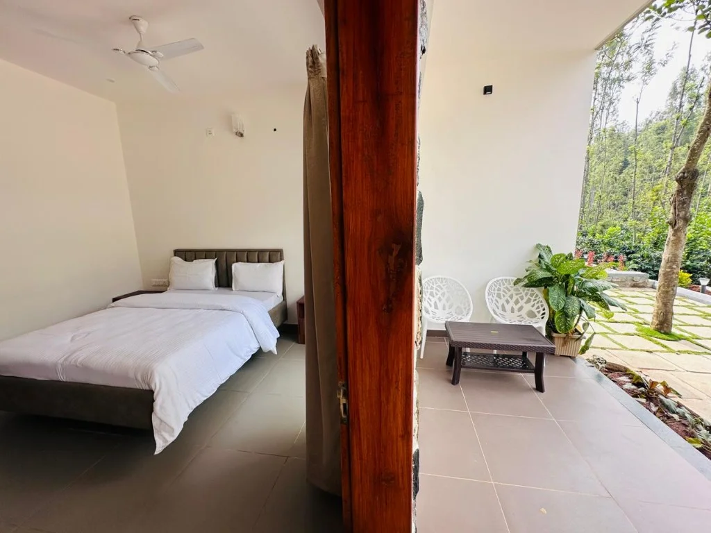 Bedroom with private patio seating and lush forest backdrop at Homestay P3