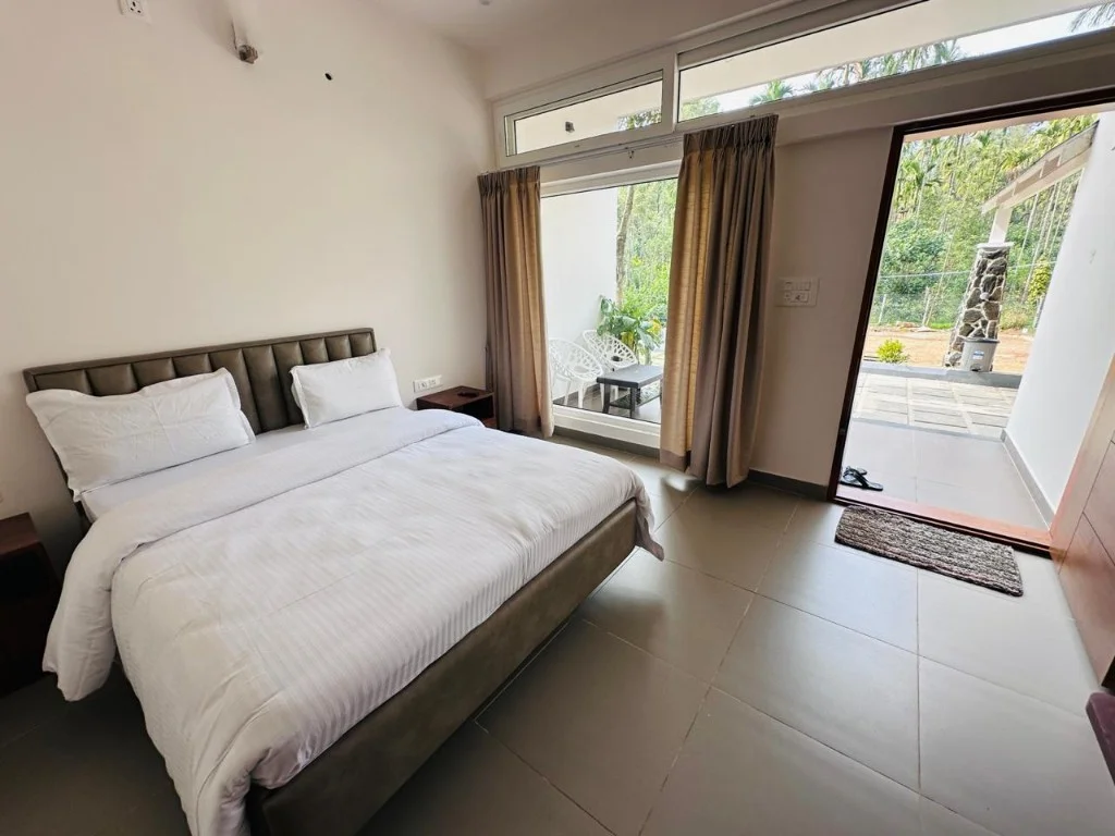 Minimal double bedroom with patio door opening to forest view at Homestay P3