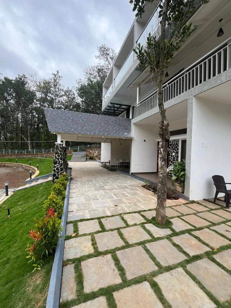 Homestay P3 three-storey white building on lush green hillside in Chikmagalur