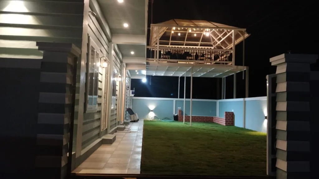 Homestay P3 courtyard with green lawn and illuminated rooftop gazebo at night