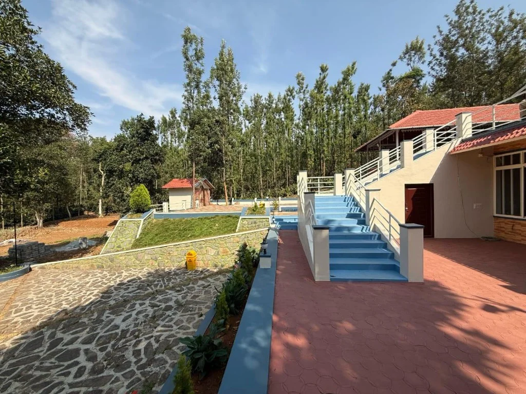 Trip Chikmagalur Resort P2 exterior with blue staircase and cream building in forest setting