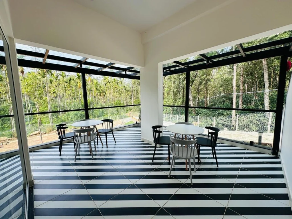 Indoor-outdoor lounge with black and white striped floor and forest views at Homestay P3