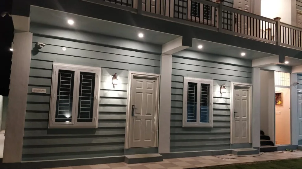Ground floor rooms with checkered walkway and warm exterior lighting at Homestay P3