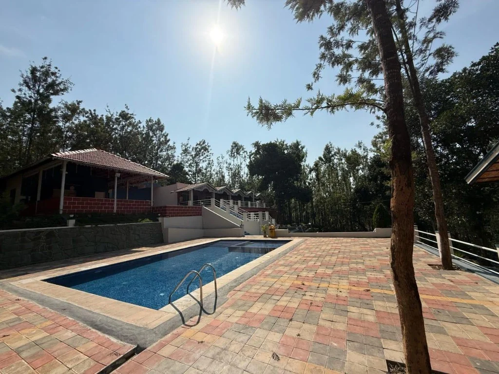 Resort P2 pool area with red-tiled pavilion and guest cottages in Chikmagalur