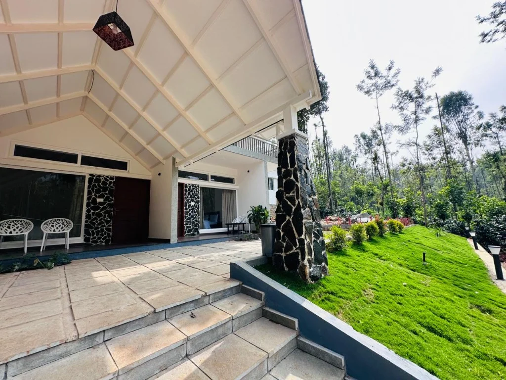 Covered porch with white chairs and manicured lawn at Homestay P3
