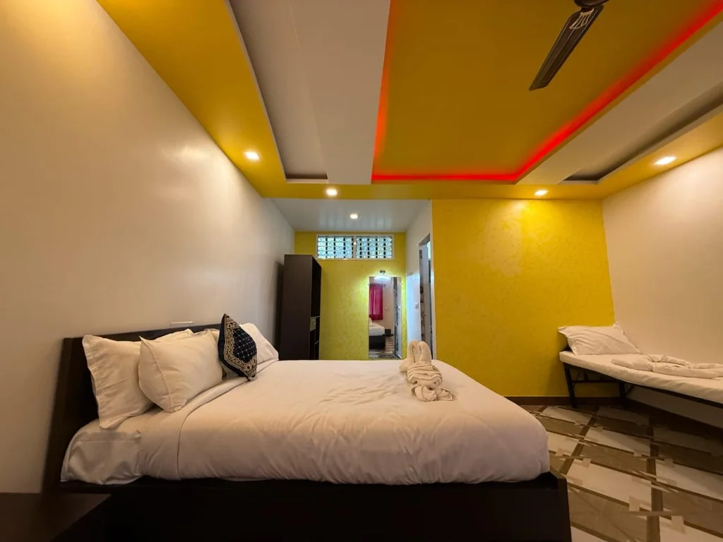 Bright family bedroom with yellow accent wall and extra cot at Trip Chikmagalur Resort P2