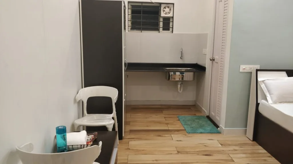 Studio room with kitchenette sink, wardrobe and seating at Homestay P3